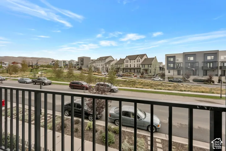 Elevated outdoor balcony with black metal railing overlooking the surrounding neighborhood and mountain landscape