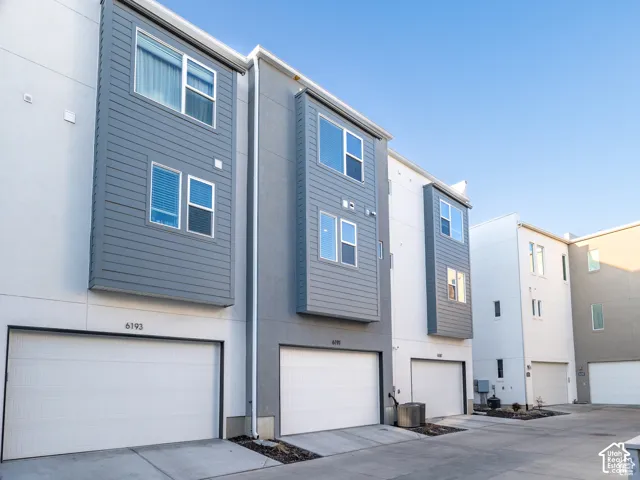 Multi-level townhouse exterior featuring a modern stucco and horizontal siding facade, paired with private multi-car garages and concrete driveways