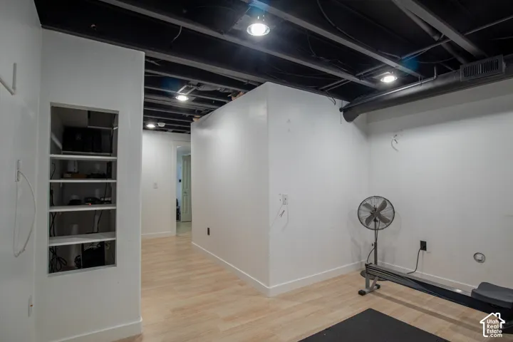 Interior space featuring wood-finish flooring, exposed industrial-style ceiling with recessed lighting, and built-in wall shelving