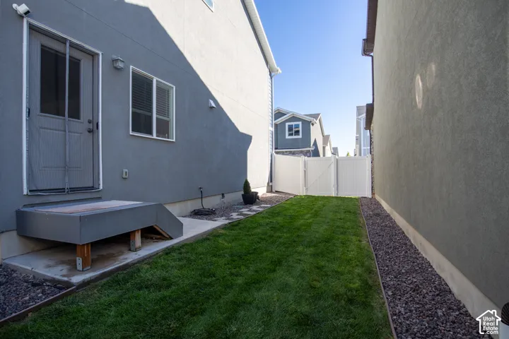 Side yard featuring a grass lawn, gravel perimeter landscaping, and white vinyl privacy fencing