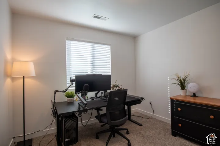 Neutral-toned walls, carpeted flooring, and a window fitted with horizontal blinds