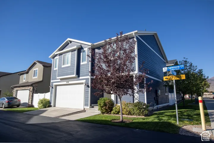 Two-story exterior featuring blue horizontal siding, white trim accents, a front-facing attached two-car garage, and concrete driveway