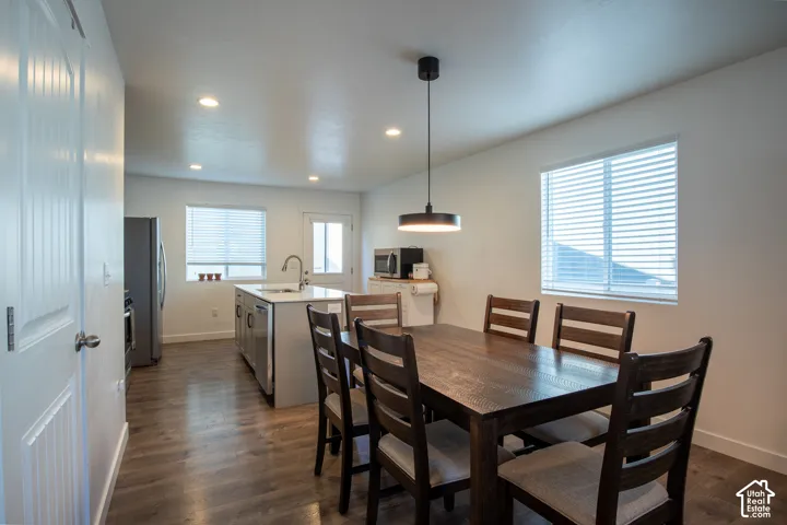 Kitchen featuring a central island with a stone countertop and under-mount sink, wood-finish flooring, recessed lighting, and a modern drum-style pendant light fixture