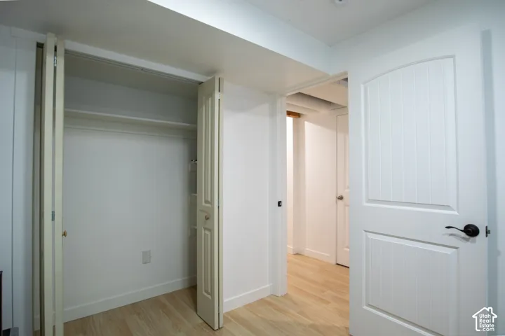 Closet featuring bi-fold doors and integrated shelving, wood-finish flooring, and white two-panel interior doors with matte black hardware