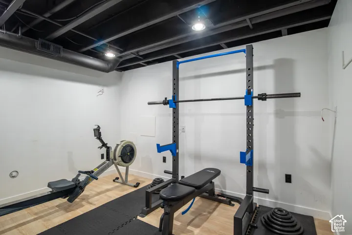Interior space featuring wood-finish flooring, exposed industrial-style ceiling with matte black finish, and recessed lighting