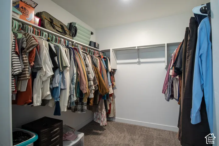 Walk-in closet featuring white wall-mounted shelving and integrated hanging rods