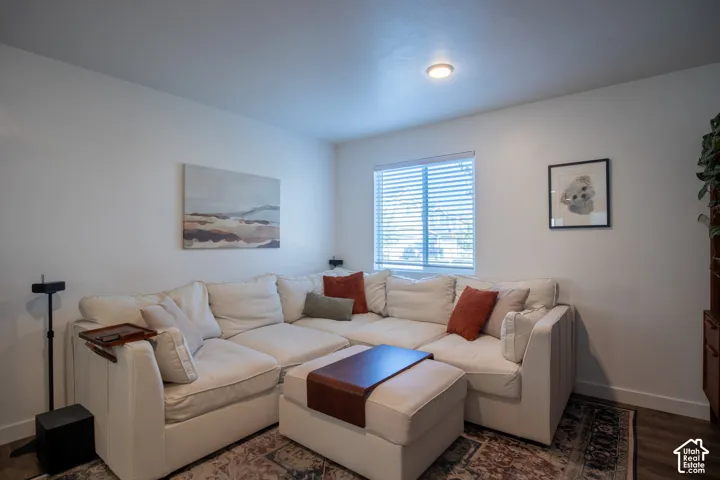 Neutral-toned interior space featuring wood-finish flooring, a single-pane window with horizontal blinds, and a flush-mount ceiling light fixture