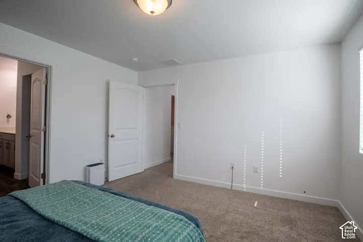 Neutral-toned interior space featuring neutral wall-to-wall carpeting, white interior doors with arched panels, and a semi-flush mount ceiling fixture
