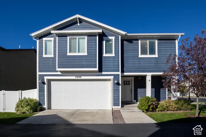 Two-story exterior featuring blue horizontal siding, white trim accents, a front-facing attached two-car garage, and a covered entryway
