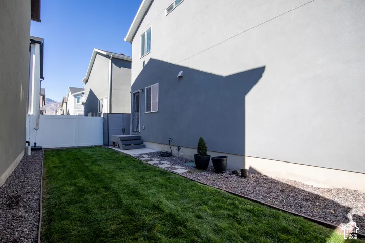 Side yard featuring a grass lawn, gravel landscape edging, and a vinyl privacy fence