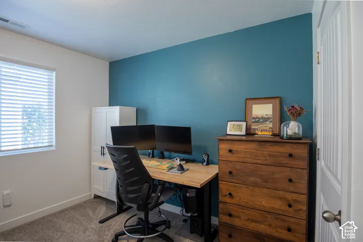 Room featuring a deep blue accent wall, neutral carpeting, and horizontal slat window blinds