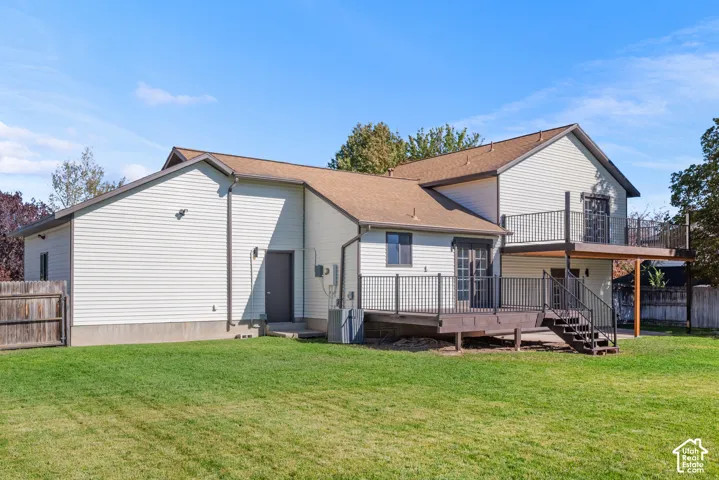 Exterior featuring light-colored siding, two-story wood deck with metal railings, and a fenced backyard