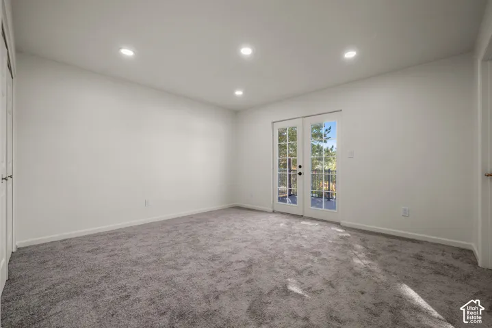 Neutral-toned wall-to-wall carpeting, recessed ceiling lighting, and double glass-paned doors with exterior access