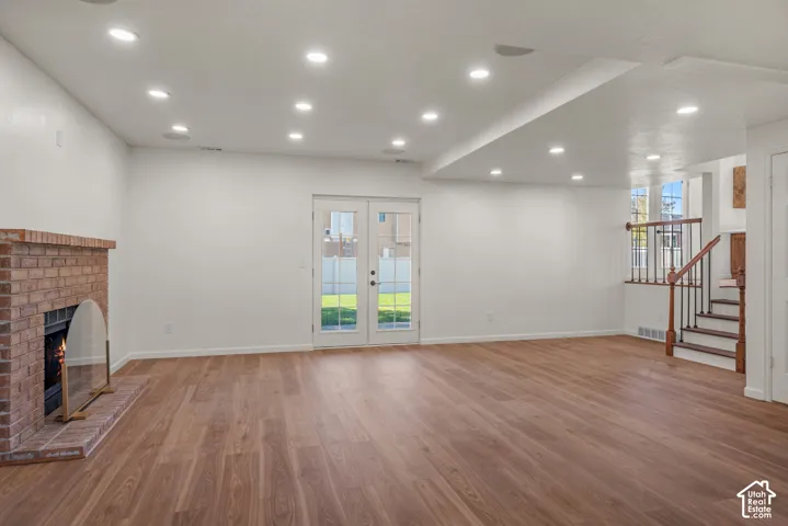 Open-concept interior featuring wood-finish flooring, a full-height brick fireplace, recessed lighting, and dual glass-panel patio doors