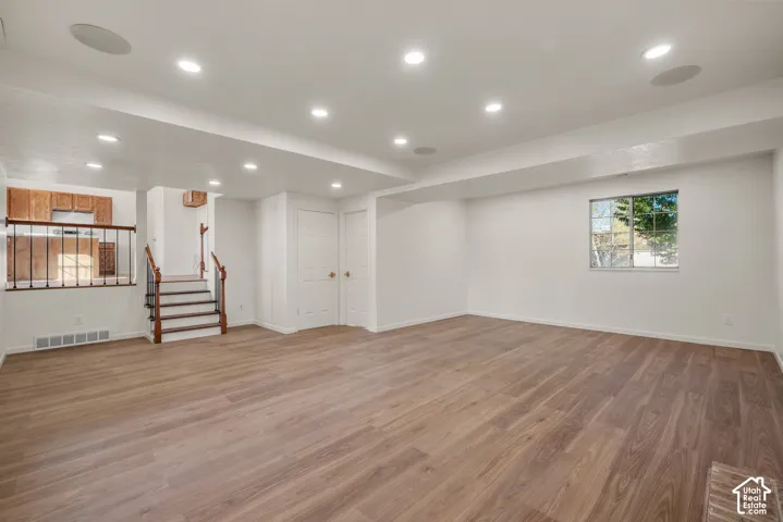 Open-concept interior featuring wood-finish flooring, recessed lighting, and a staircase with a wooden handrail and metal balusters