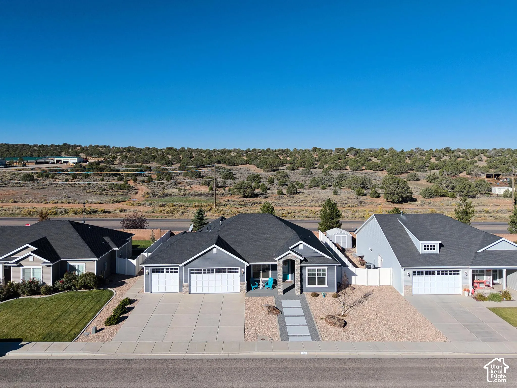 Single-story residence featuring a gray exterior, stone facade accents, a three-car garage, and a structured concrete paver walkway