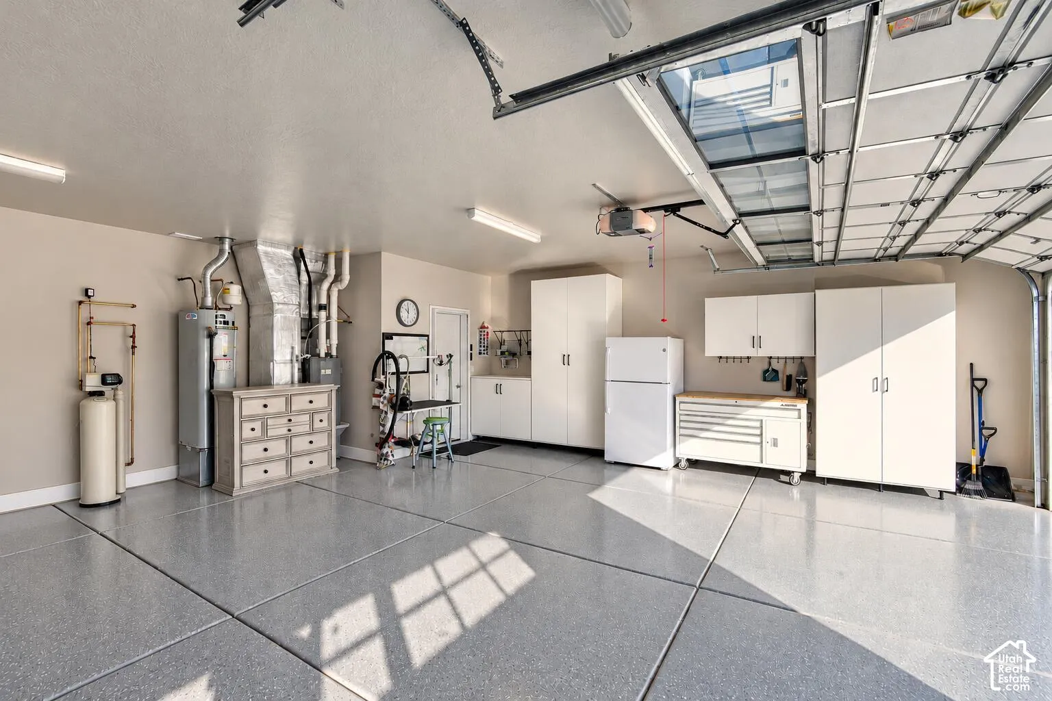 Multi-car garage featuring epoxy flooring, built-in cabinetry, overhead lighting, and an integrated water filtration system