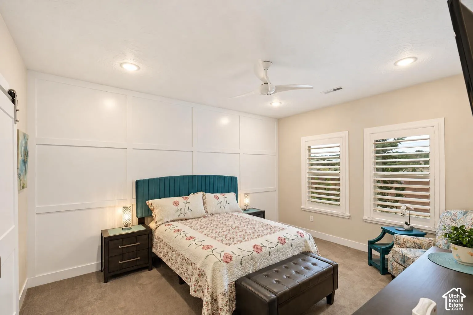 Wall-to-wall carpeting, recessed ceiling lighting, ceiling fan with integrated light fixture, grid-pattern wall molding, and dual windows with plantation shutters