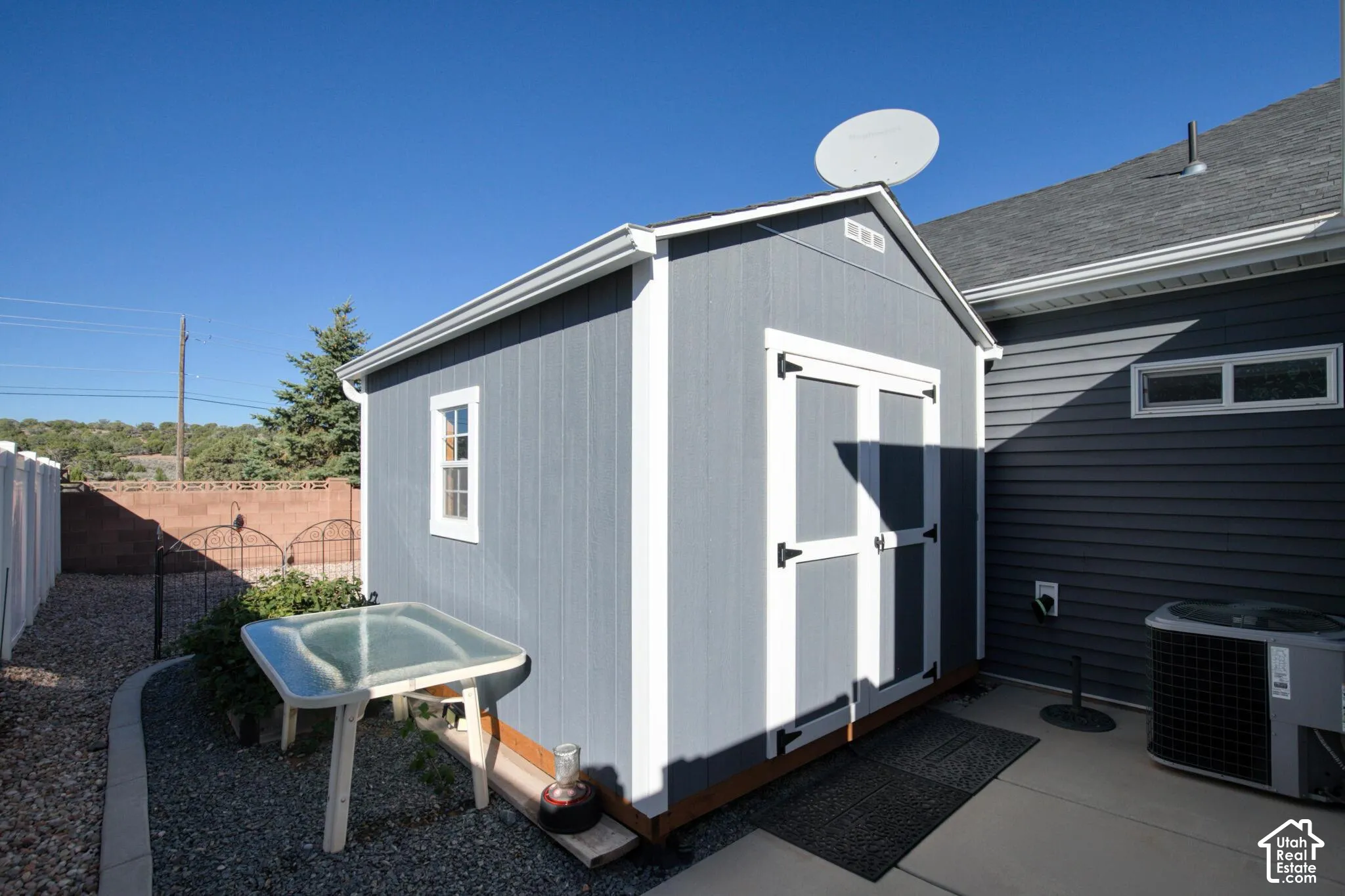 Detached storage structure featuring gray painted siding, white trim, dual entry doors, and a single-pane window