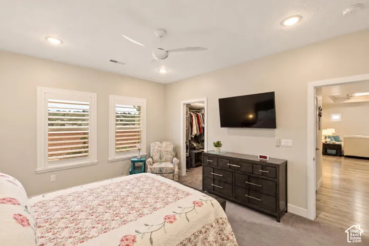 Bedroom featuring recessed lighting, white window shutters, a ceiling fan, and a walk-in closet