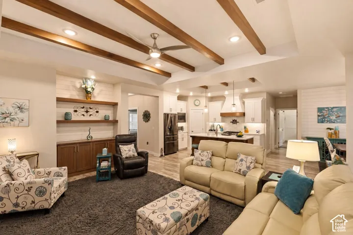Coffered ceiling with exposed wood beams, recessed lighting, built-in cabinetry with floating shelving, shiplap wall accents, and a center kitchen island