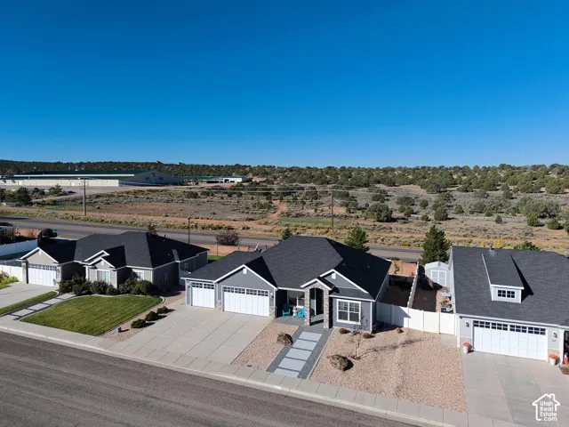 Single-level residence featuring a multi-car garage, stone-accented exterior, low-maintenance landscaping, paved walkway, and a private side-yard enclosure