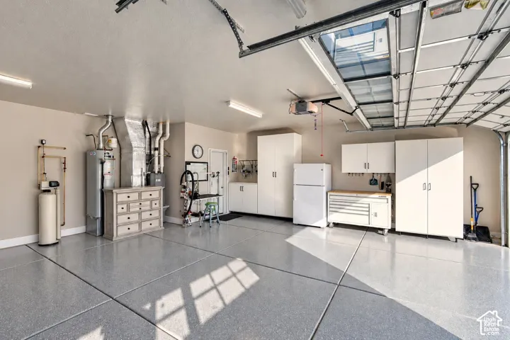Multi-car garage featuring epoxy flooring, built-in cabinetry, overhead lighting, and an integrated water filtration system