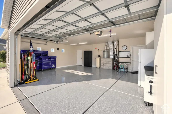 Attached garage featuring an epoxy-coated concrete floor, finished interior walls, recessed lighting, and side-entry door