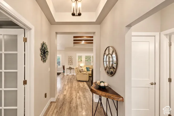 Entryway featuring a tray ceiling with a multi-bulb flush mount light fixture, wood-finish flooring, and French door entry