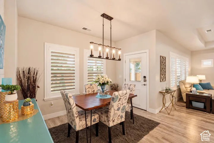 Dining area featuring wood-finish flooring, plantation shutters, and a modern five-light rectangular chandelier