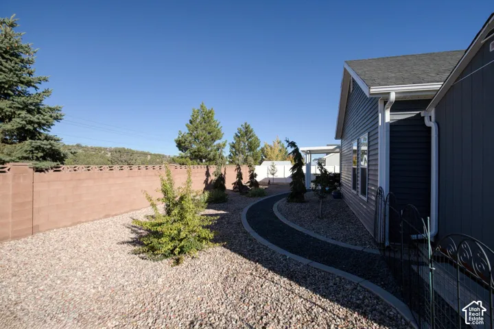 Side yard featuring a decorative gravel pathway, xeriscaped ground cover, mature landscaping, and a masonry perimeter wall