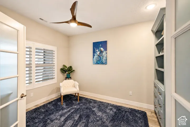 Built-in floor-to-ceiling cabinetry with integrated drawers, wood-finish flooring, recessed lighting, ceiling fan with three blades, and plantation shutters