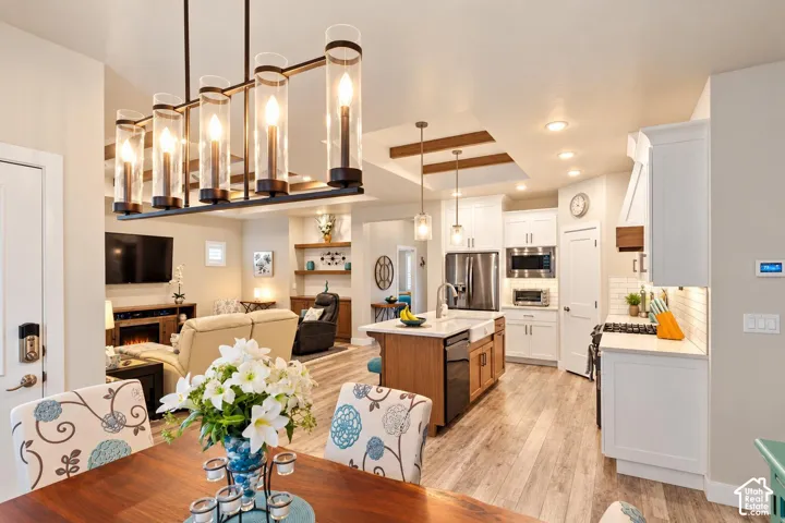 Kitchen featuring a center island with farmhouse sink, shaker-style cabinetry, stainless steel appliances, and a coffered ceiling with wood beams