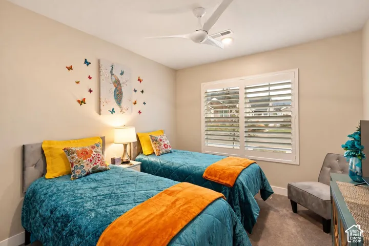 Neutral-toned interior featuring plantation shutters, carpeted flooring, and a modern ceiling fan