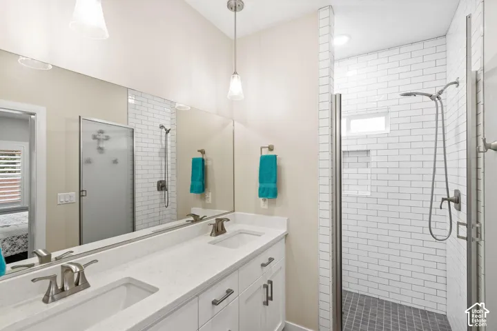 Double vanity with white cabinetry and solid-surface countertops, walk-in shower with white subway tile surround, mosaic floor tile, and built-in recessed wall shelving