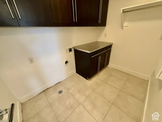 Dark-finish cabinetry, metal countertop, tile flooring, and wall-mounted shelving