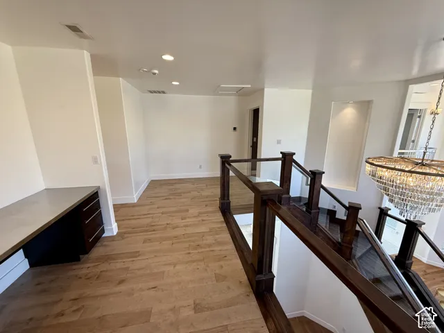 Wood-finish flooring, built-in cabinetry desk, recessed lighting, and a staircase featuring a wooden handrail with glass paneling
