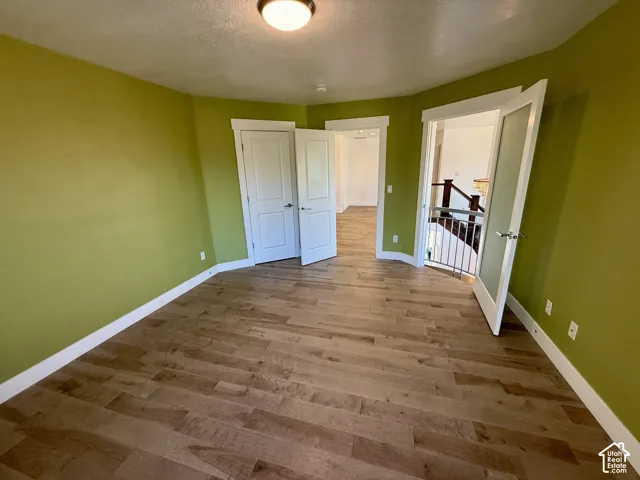 Bedroom 2 featuring wood-finish flooring, white paneled interior doors, high-profile trim, and a ceiling-mounted flush light fixture