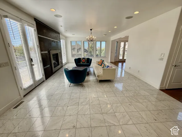 Polished marbel tile flooring, floor-to-ceiling wood wall with integrated fireplace, recessed ceiling lighting, decorative chandelier, and tall multi-pane windows for valley views.