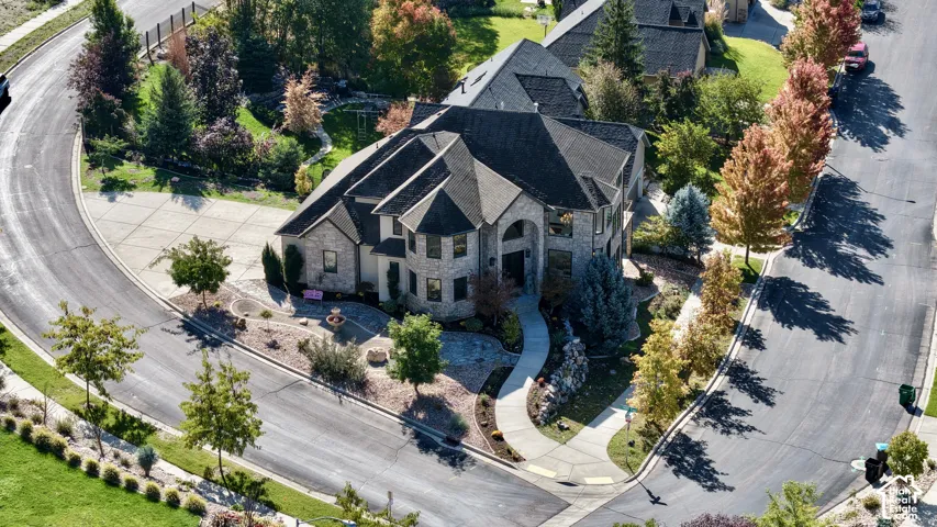 Multi-story stone exterior featuring an arched entryway, steep roofline, turret-style facade, and a concrete driveway on a corner lot