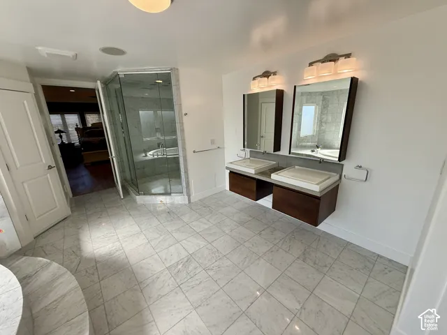 Dual floating vanities with vessel sinks and integrated medicine cabinets, stone tile flooring, and a glass-enclosed shower with tile surround