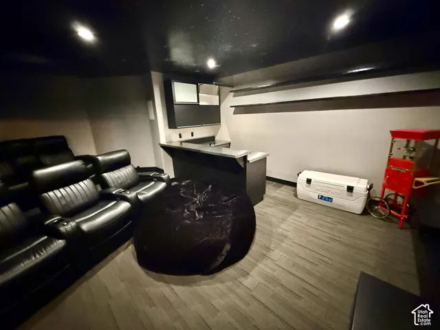 Dedicated media space featuring a built-in bar, custom cabinetry, recessed ceiling lighting, and wood-finish flooring