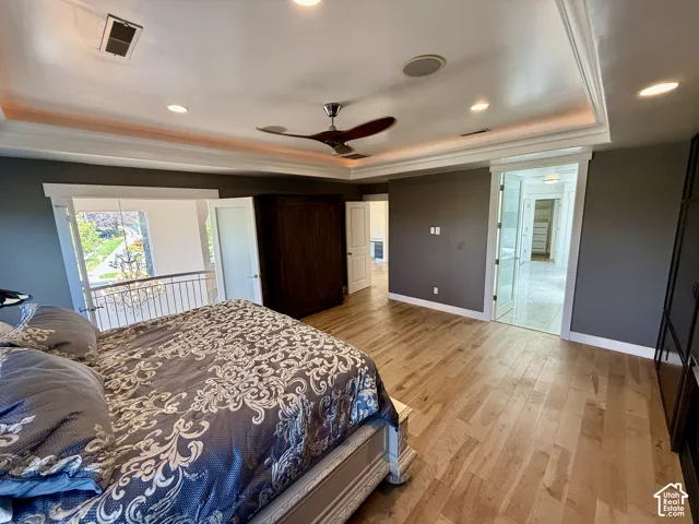 Master bedroom with Tray ceiling with recessed lighting, wood-finish flooring, ceiling fan