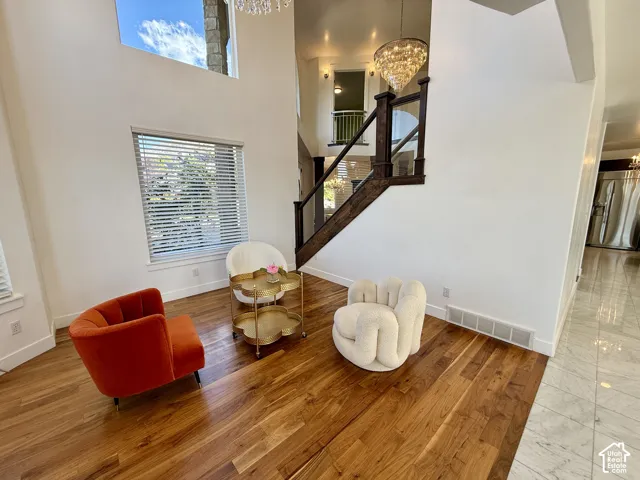 Vaulted ceilings with expansive windows, dark-stained wood-finish flooring, staircase with a custom wood railing, and tiered crystal pendant lighting