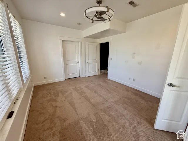 bedroom 4 Interior space featuring carpeted flooring, two-panel interior doors, adjustable horizontal window blinds, and a contemporary drum-style ceiling fan with integrated lighting