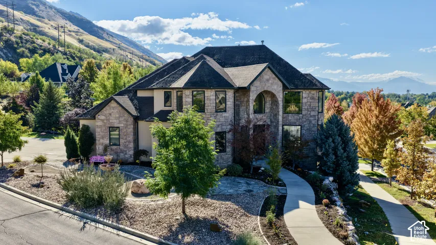 Multi-story exterior featuring stone cladding, a steep-pitched roofline, an arched entryway, and concrete walkway