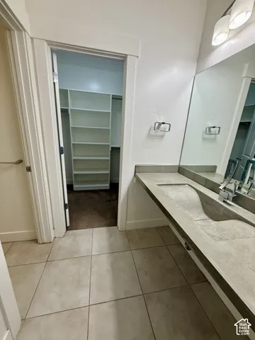 Bedroom 5 Jack and Jill bath Concrete vanity with integrated sink, large-format tile flooring, built-in shelving, and wall-mounted light fixture