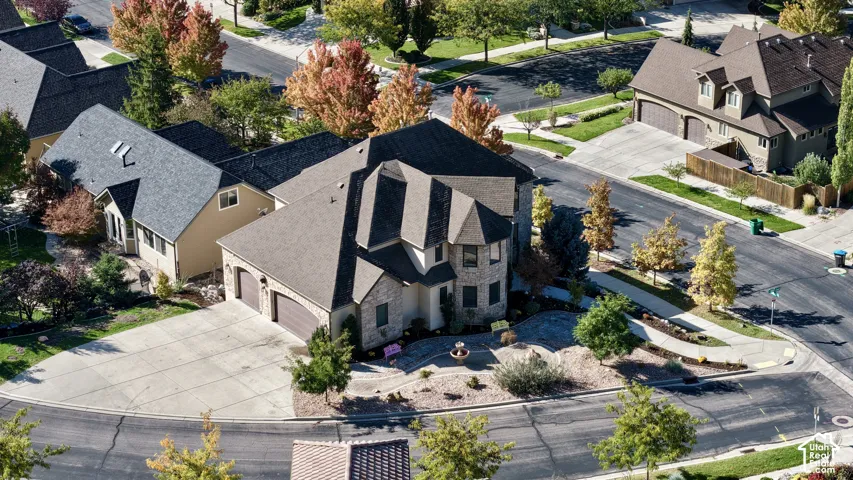 Multi-level residence featuring a stone and siding exterior, multi-pitched shingle roof, attached three-car garage, and hardscaped front courtyard