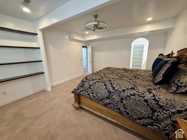 Bedroom 5 Built-in wall shelving with dark-toned surfaces, neutral carpeting, recessed ceiling lighting, and a modern drum-style chandelier and  Jack & Jill bathroom
