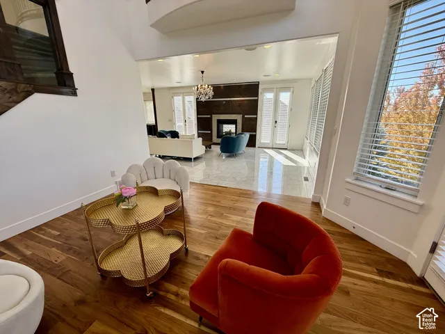 Brazilian Cheery Wood-finish flooring, stone tile flooring, floor-to-ceiling dark wood fireplace surround, recessed ceiling lighting, and chandelier